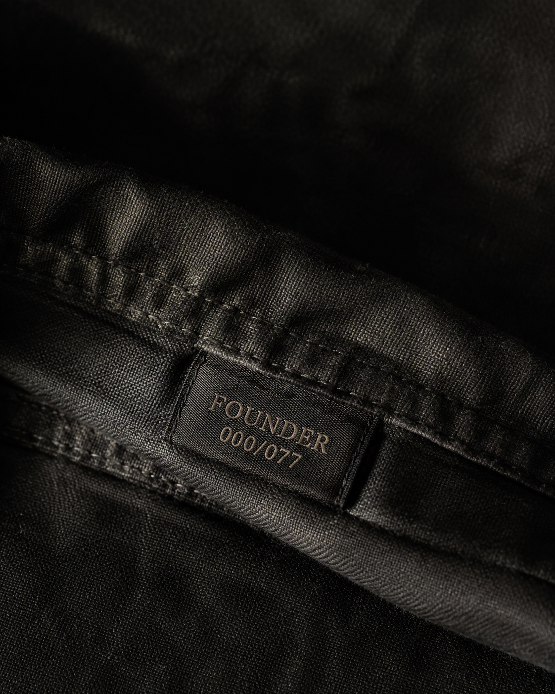 Concept close-up of a Founder 000/077 label on charcoal fabric